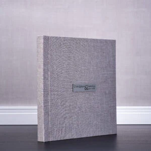 Livro de casamento com capa de tecido cinza, personalizado com nomes Derquian e Daniela. Perfeito para ocasiões especiais.