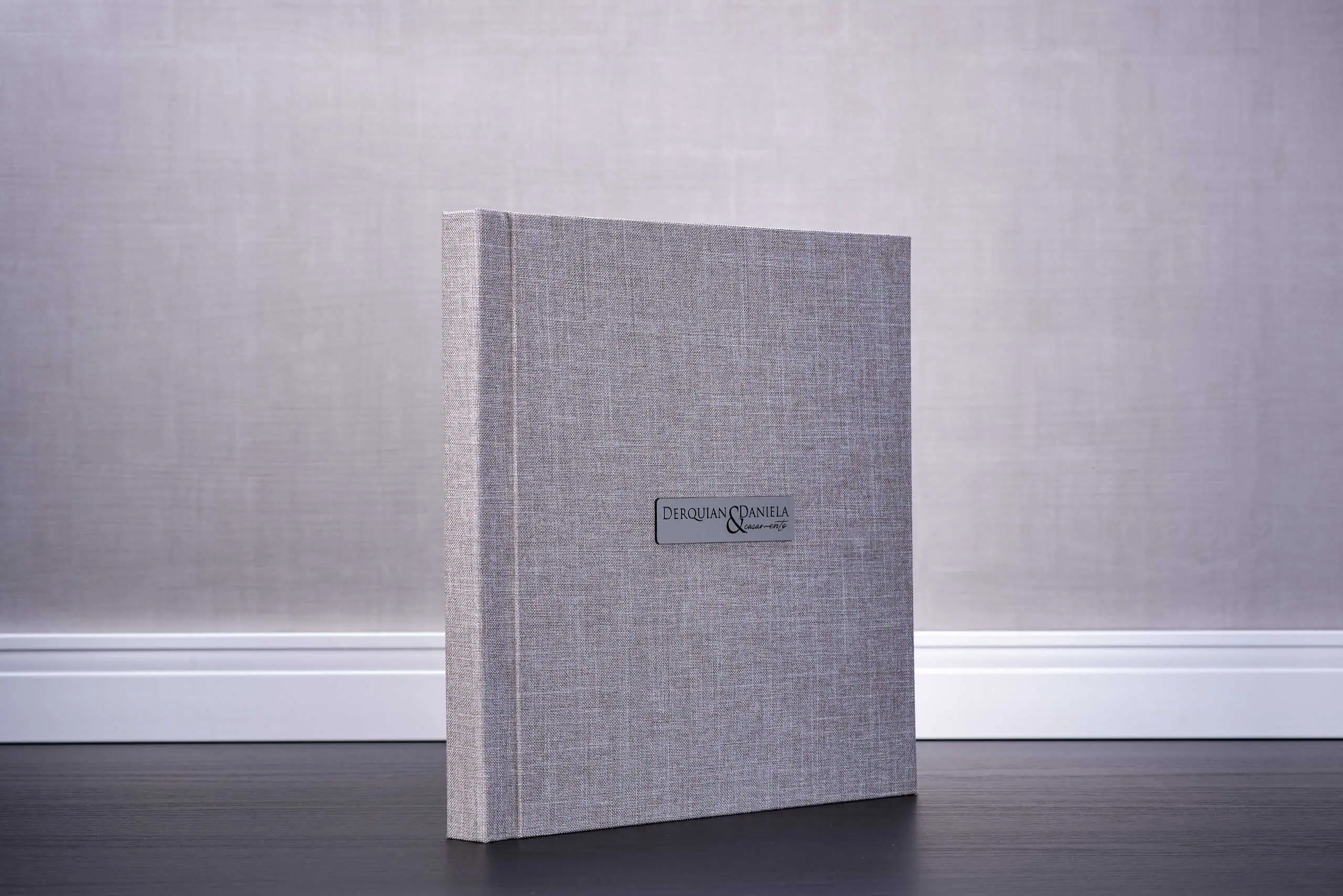 Livro de casamento com capa de tecido cinza, personalizado com nomes Derquian e Daniela. Perfeito para ocasiões especiais.