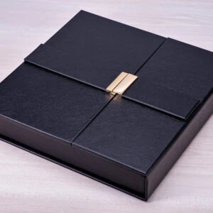 Caixa de presente elegante em couro preta com lacre dourado, ideal para ocasiões especiais.