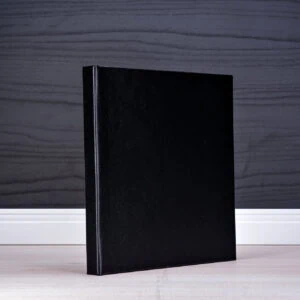 Árvore de livros pretos em fundo de paredes de madeira escura.